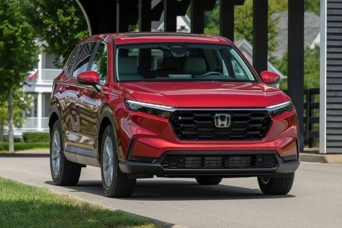 Kırmızı Honda CR-V crossover, ön çapraz açıdan çekim, ızgarada "H" logosu net görünüyor, ağaçlık bir mahalle sokağında